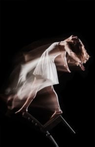 Female dancer balancing on chair.