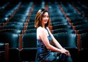 Kyra Zhao posing in theatre seats.